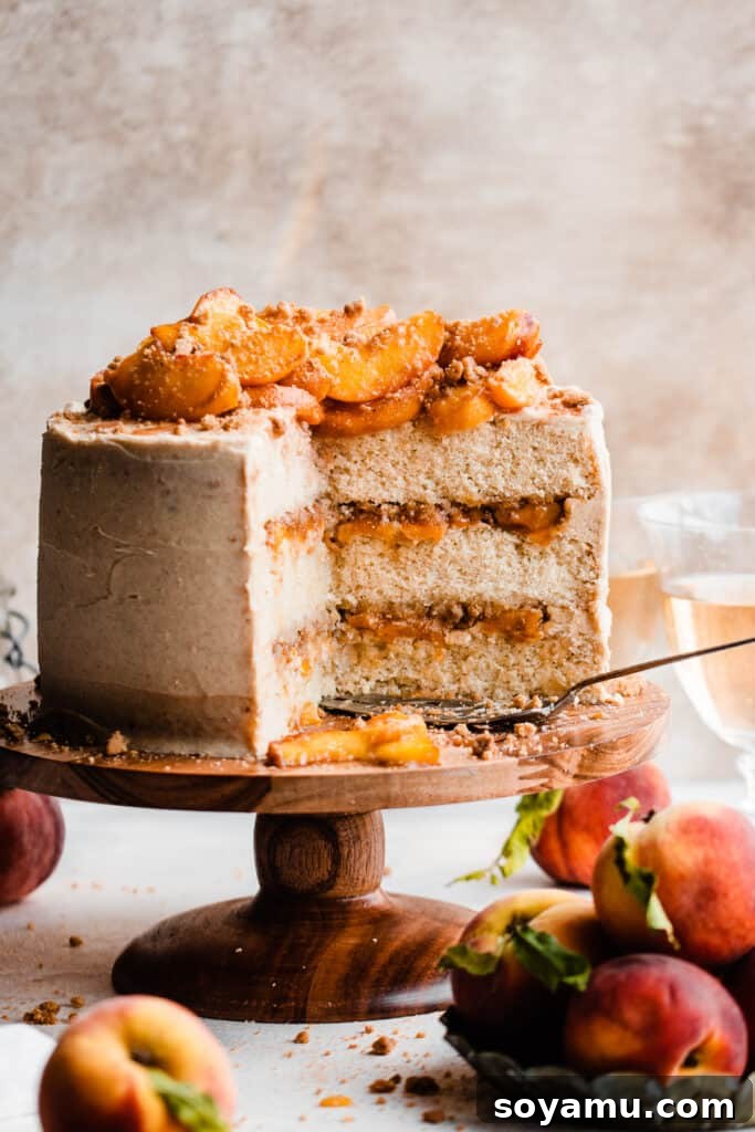 Golden Peach Cobbler Cake with Nutty Brown Butter Frosting 12 The sliced peach cobbler cake, beautifully arranged on a cake stand and topped with additional fresh peach slices, showcasing its inviting layers.