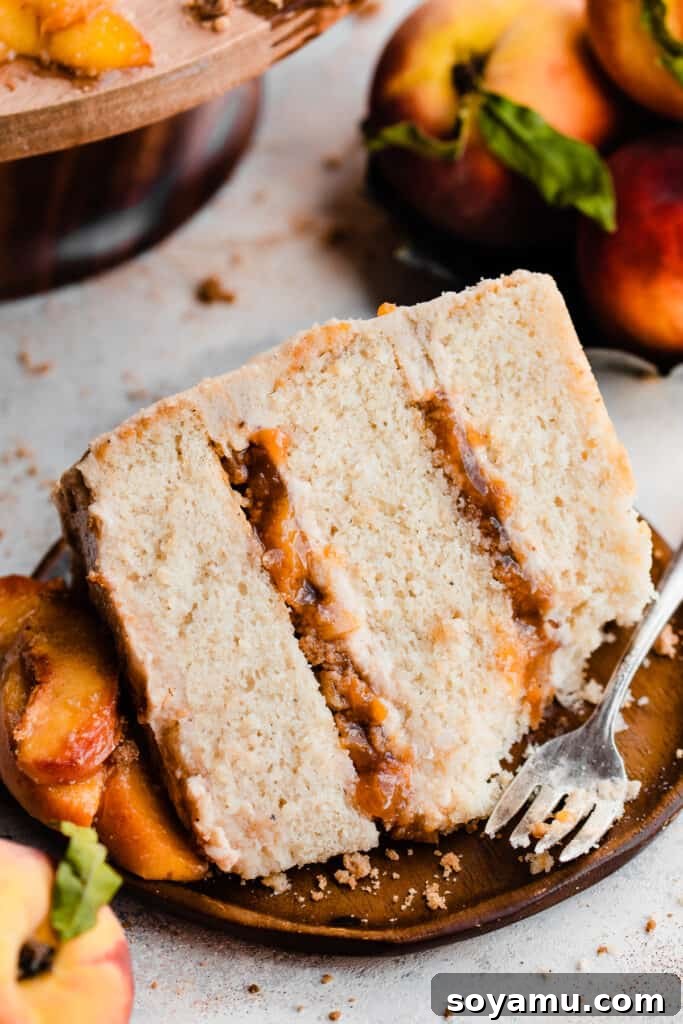 Golden Peach Cobbler Cake with Nutty Brown Butter Frosting 3 A perfectly sliced piece of peach cobbler layer cake, showcasing the layers of vanilla cinnamon cake, rich brown butter frosting, sweet homemade peach filling, and crunchy cinnamon streusel.