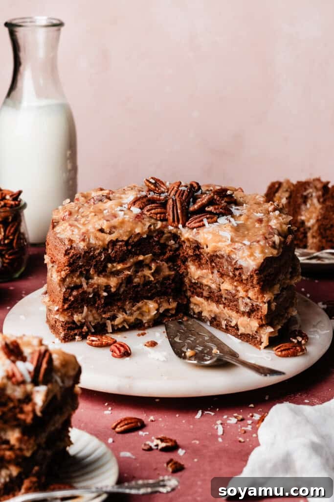 A beautifully sliced German Chocolate Cake on a elegant marble cake plate, showcasing its moist chocolate layers and generous coconut pecan frosting.
