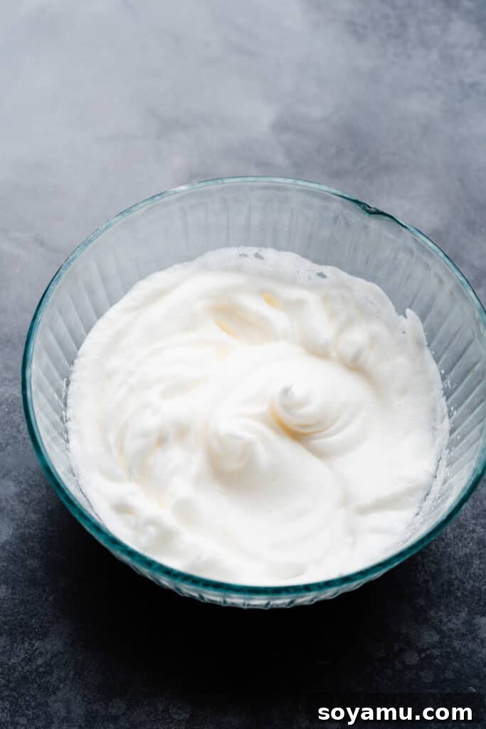 A bowl of perfectly beaten egg whites, standing tall with stiff, glossy peaks.