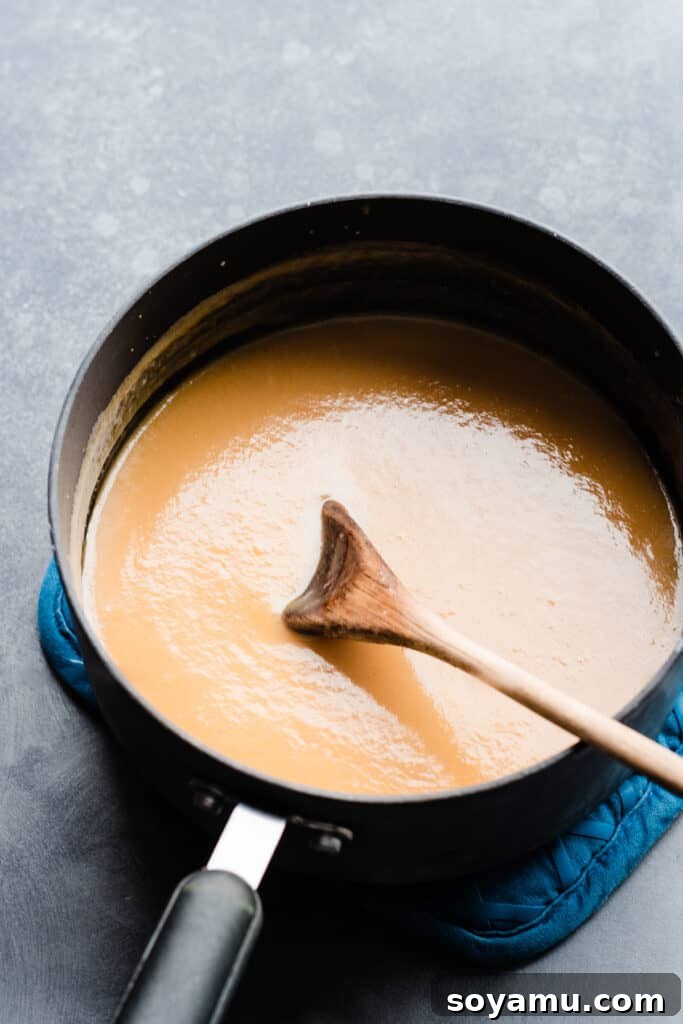 A saucepan filled with the rich, golden-brown coconut pecan frosting, simmering gently on the stove.