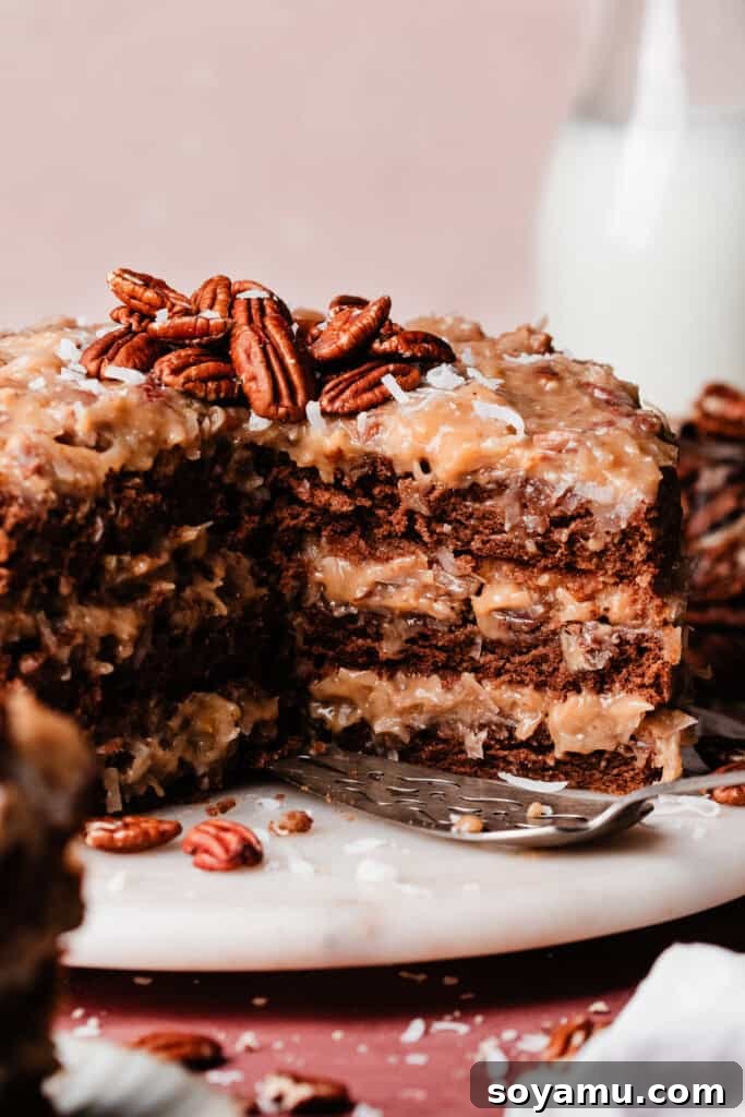 A close-up view of the interior of a sliced German Chocolate Cake, highlighting the perfectly moist chocolate layers separated by generous amounts of coconut pecan frosting.
