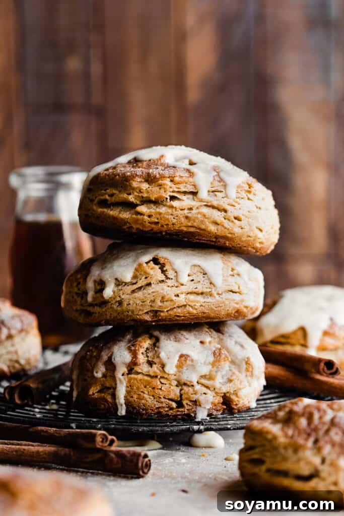 Warm Maple Biscuits with a Velvety Maple Glaze 9 A beautifully stacked trio of flaky maple biscuits with a rustic wooden background, highlighting their height and texture.