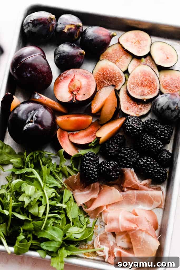 Luscious Fig & Honey Ricotta Toast 6 A variety of colorful toast toppings laid out on a sheet pan, including freshly sliced figs, plums, green arugula, and dark blackberries.