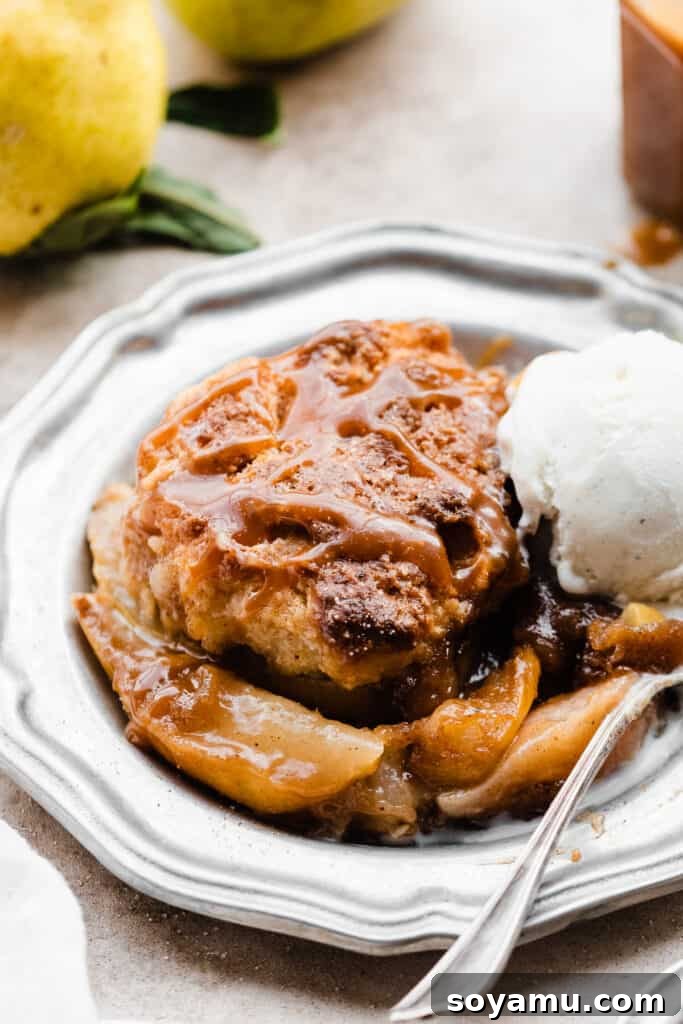 Caramel Sea Salt Pear Cobbler 3 A pristine plate showcasing a serving of golden pear cobbler, generously topped with a melting scoop of vanilla ice cream and an artistic drizzle of glistening salted caramel sauce.