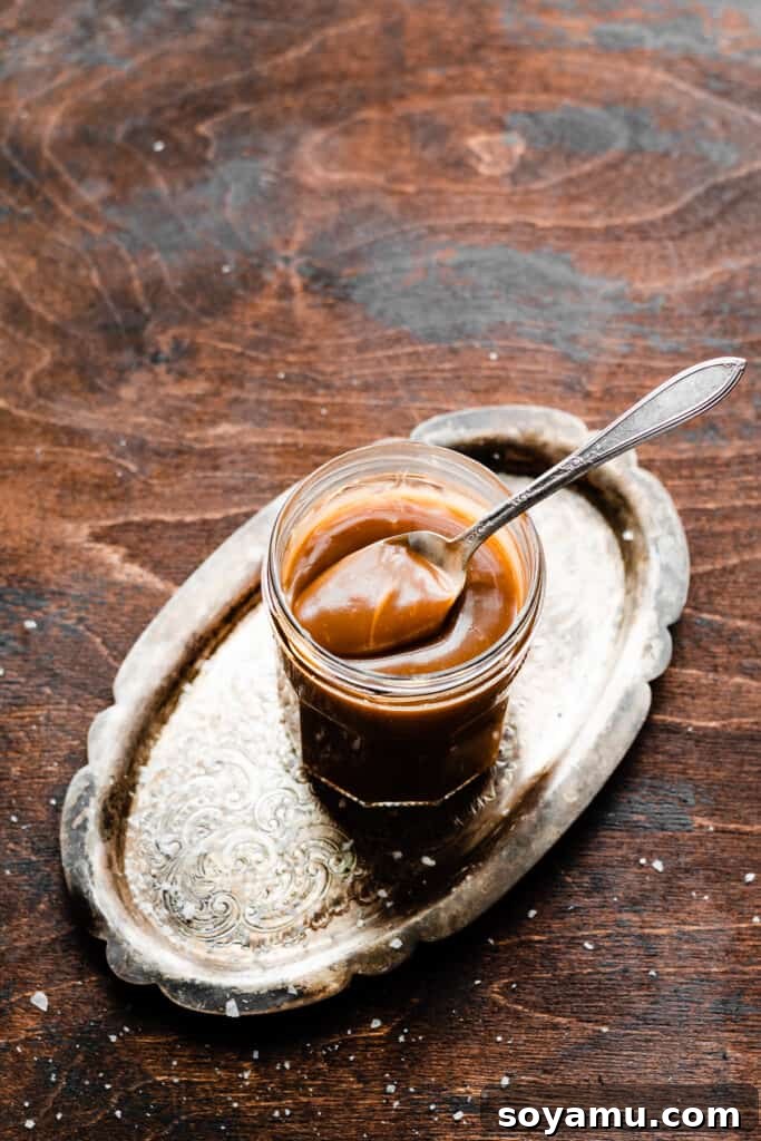 Caramel Sea Salt Pear Cobbler 4 A charming glass jar filled with rich, golden salted caramel sauce, resting on a rustic wooden surface, highlighting its luscious texture.
