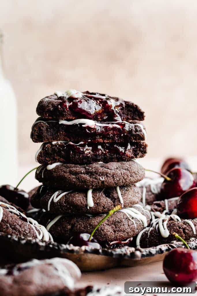 Midnight Forest Cherry Cookies 3 A stack of Black Forest Cookies on a vintage metal tray, with the top cookies broken open to reveal their soft, fudgy chocolate interiors and glistening cherry filling.