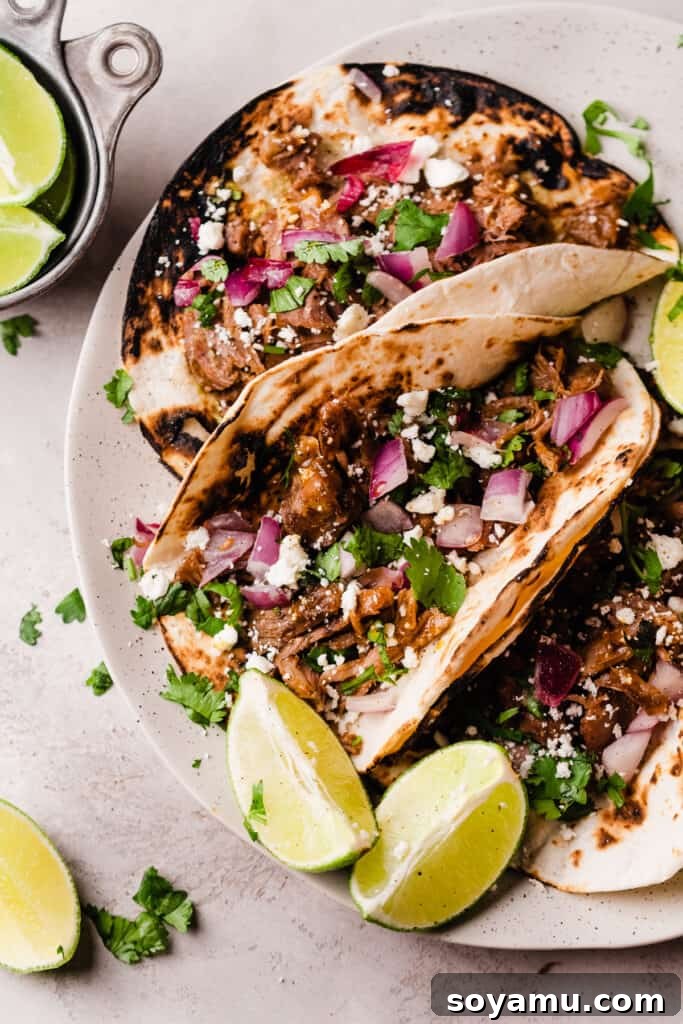 Melt-in-Your-Mouth One-Pot Lamb Barbacoa Tacos 3 Platter of delicious lamb barbacoa tacos, garnished with fresh red onion, cotija cheese, lime wedges, and cilantro, ready to be devoured.