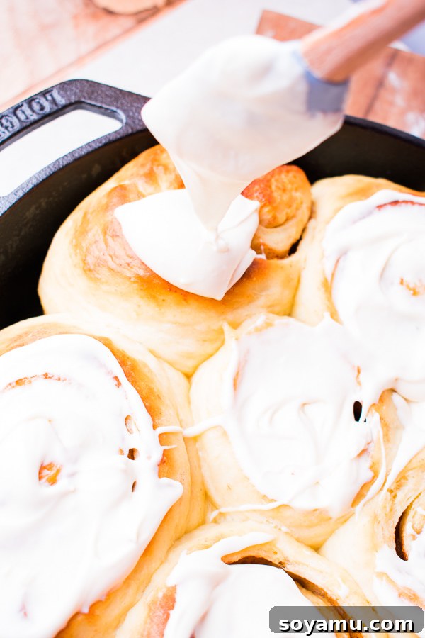 Close-up of baked cinnamon rolls in a cast iron pan, showing their golden crust and soft interior.