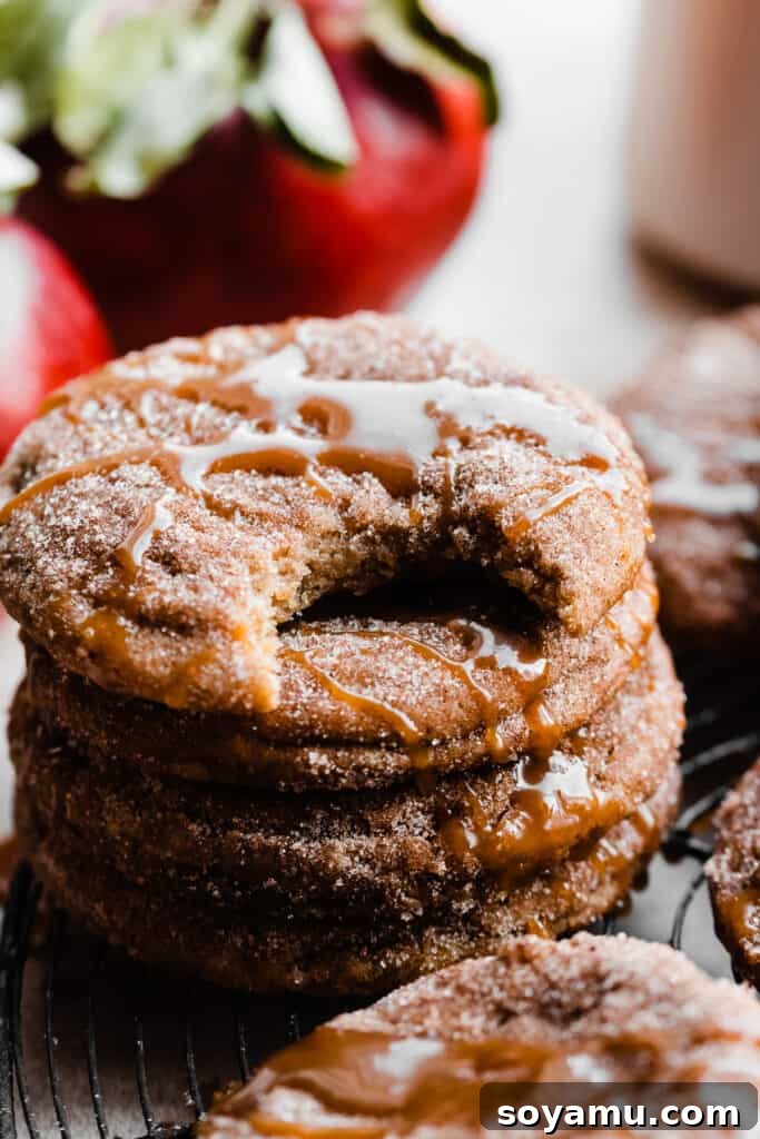 Spiced Caramel Apple Cider Cookies 9 A delectable close-up on a stack of caramel apple cider cookies, with a tempting bite taken out of the top cookie, revealing its soft interior.