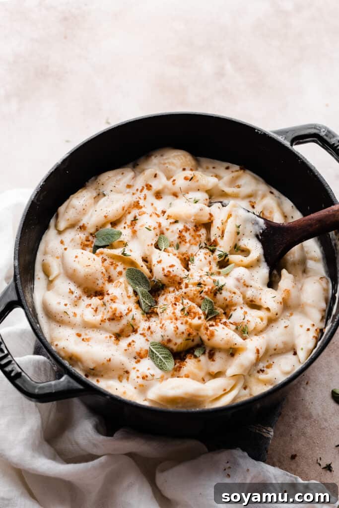 Creamy White Cheddar Mac with Crispy Brown Butter Crumbs 10 A large pot filled with the steaming, creamy white cheddar mac and cheese, garnished with fresh herbs.