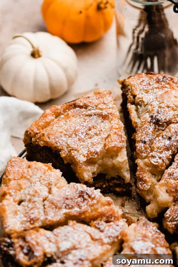 Decadent Pumpkin Gooey Butter Cake 4 A close-up on a perfectly sliced piece of pumpkin gooey butter cake with a bite missing, showcasing its layered texture and crackly crust.
