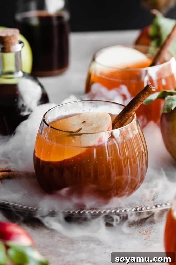 A glass of witches brew punch on a silver tray, with swirls of smoke dancing around.