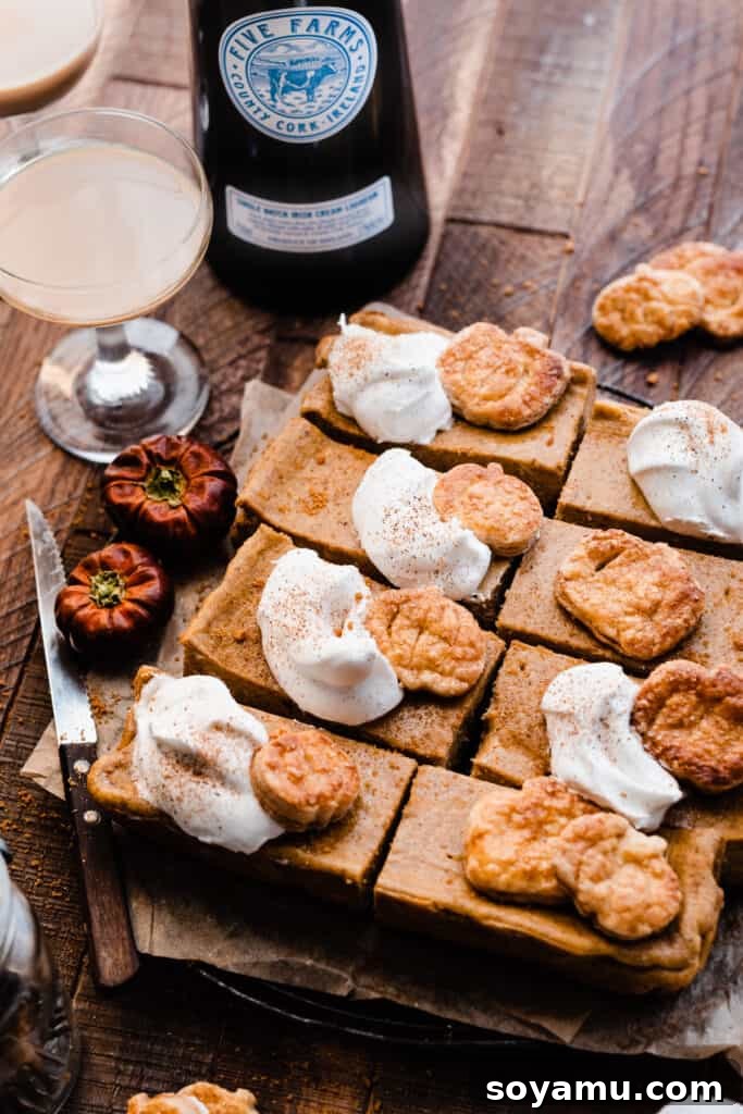 Velvet Pumpkin Irish Cream Cheesecake Bars 10 A rustic wooden surface featuring sliced pumpkin cheesecake bars topped with whipped cream, accompanied by glasses of Five Farms Irish Cream, perfect for a cozy fall evening.
