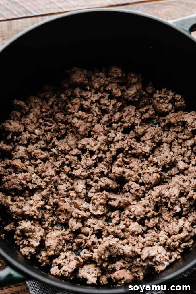 A Dutch oven containing perfectly cooked and seasoned ground lamb, ready for the next steps.