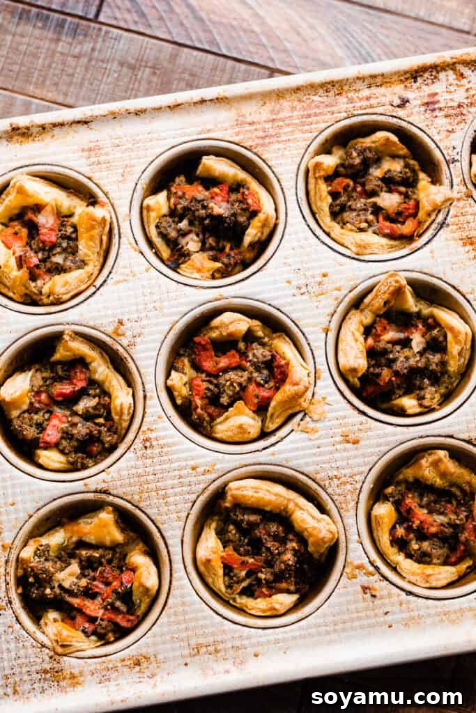Freshly baked lamb appetizer cups, golden and crisp, cooling in a muffin pan after emerging from the oven.