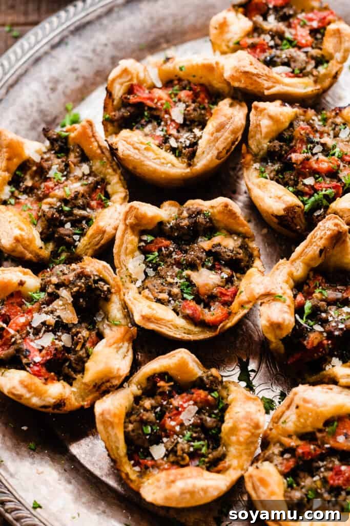 A vibrant close-up of the perfectly baked lamb appetizer cups, showcasing their golden crust and savory filling, arranged on a serving tray.