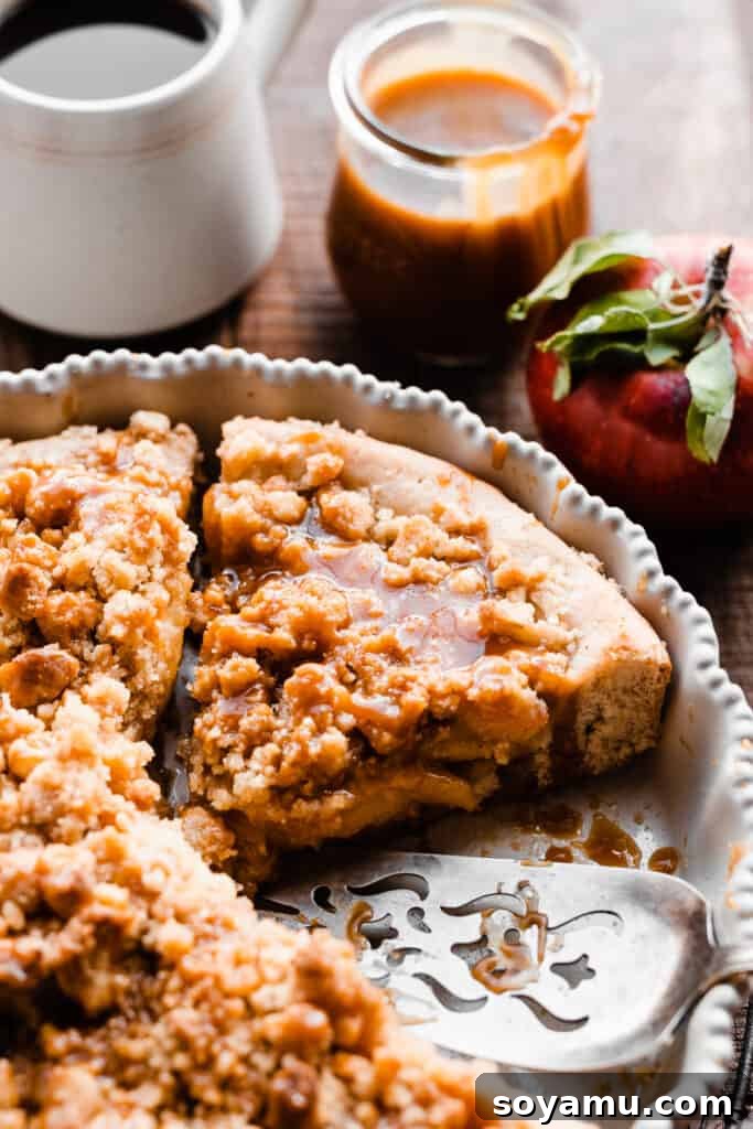 Decadent Caramel Apple Streusel Pizza 2 A close-up on a slice of caramel apple dessert pizza in the pie plate, showing the tender apples and streusel topping.