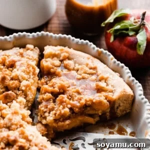 A close-up on a slice of apple pizza in the pie plate, with salted caramel sauce.