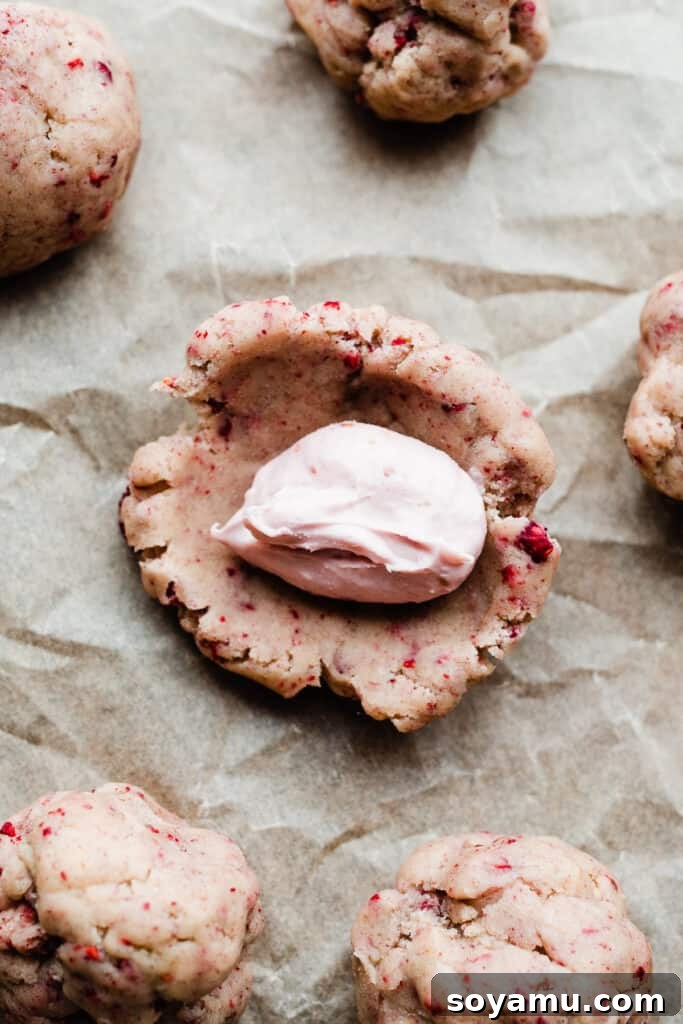 Luscious White Chocolate Raspberry Cheesecake Cookies 6 A cookie dough ball, expertly flattened and ready to be stuffed with a frozen cheesecake dollop in its center.
