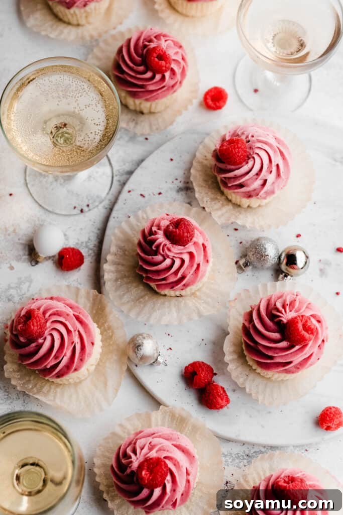 Pink Champagne Raspberry Delights 10 A delightful bird's eye view of the raspberry champagne cupcakes arranged elegantly on a marble surface, accompanied by glasses of champagne.