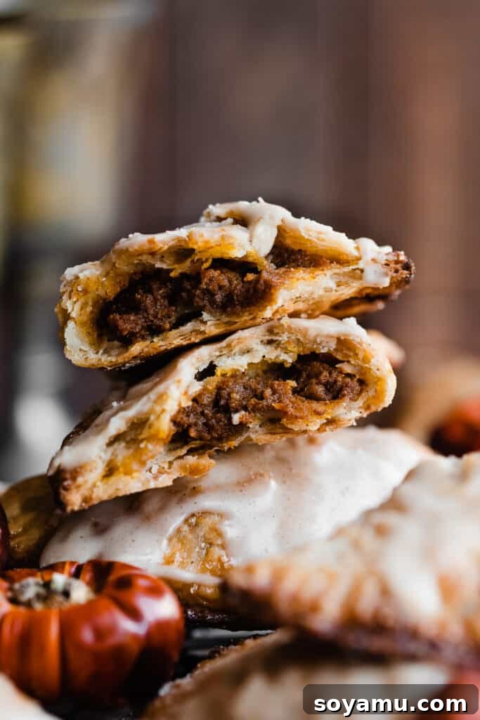 Golden Maple Glazed Pumpkin Pasties 8 Broken open halves of a pumpkin pasty stacked together, revealing the rich filling and textured crust.