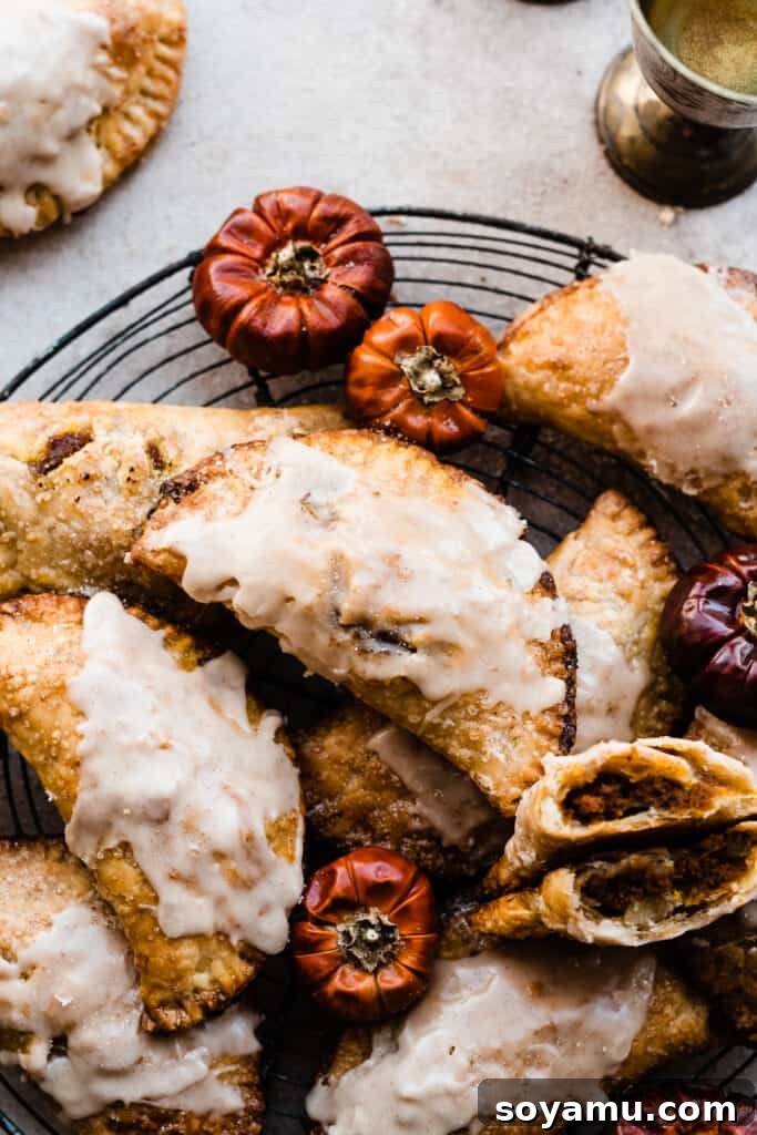 Golden Maple Glazed Pumpkin Pasties 9 Pumpkin Pasties with maple glaze on a wire rack on a light surface, ready to be served.