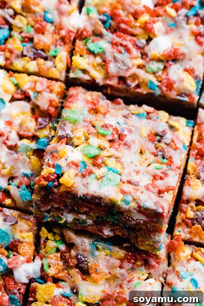 Slices of brown butter Fruity Pebbles treats, perfectly arranged and drizzled with a sweet cereal glaze, ready for serving.