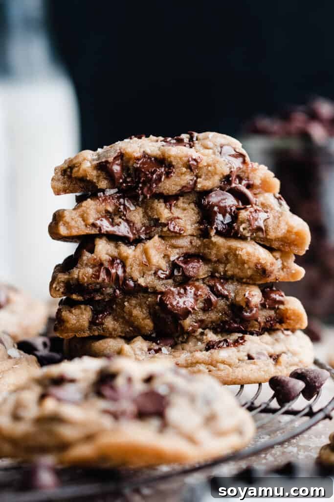 A stack of broken open cookies, showing their gooey insides, studded with melty chocolate chips.