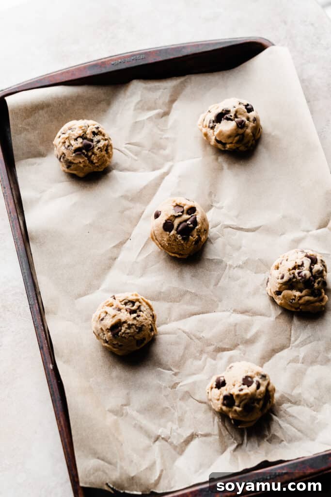 Chocolate chip cookie dough balls on a baking sheet.