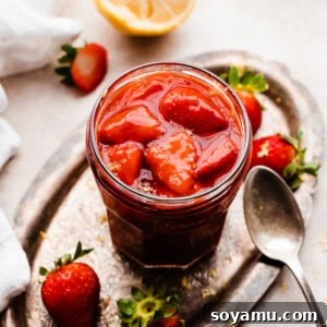 Easy 10-Minute Strawberry Compote 9 A jar of homemade strawberry compote on a vintage metal tray, with berries gleaming.