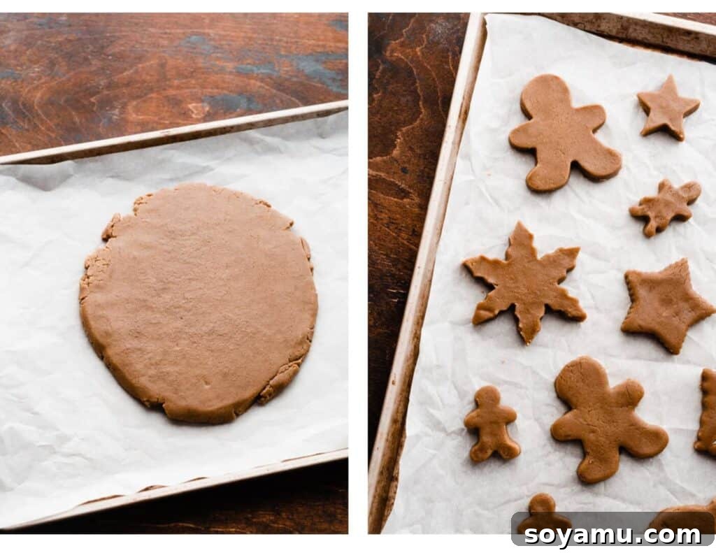 A close-up of rolled gingerbread dough between two sheets of parchment paper, with various cookie cutters arranged on top, ready for cutting.