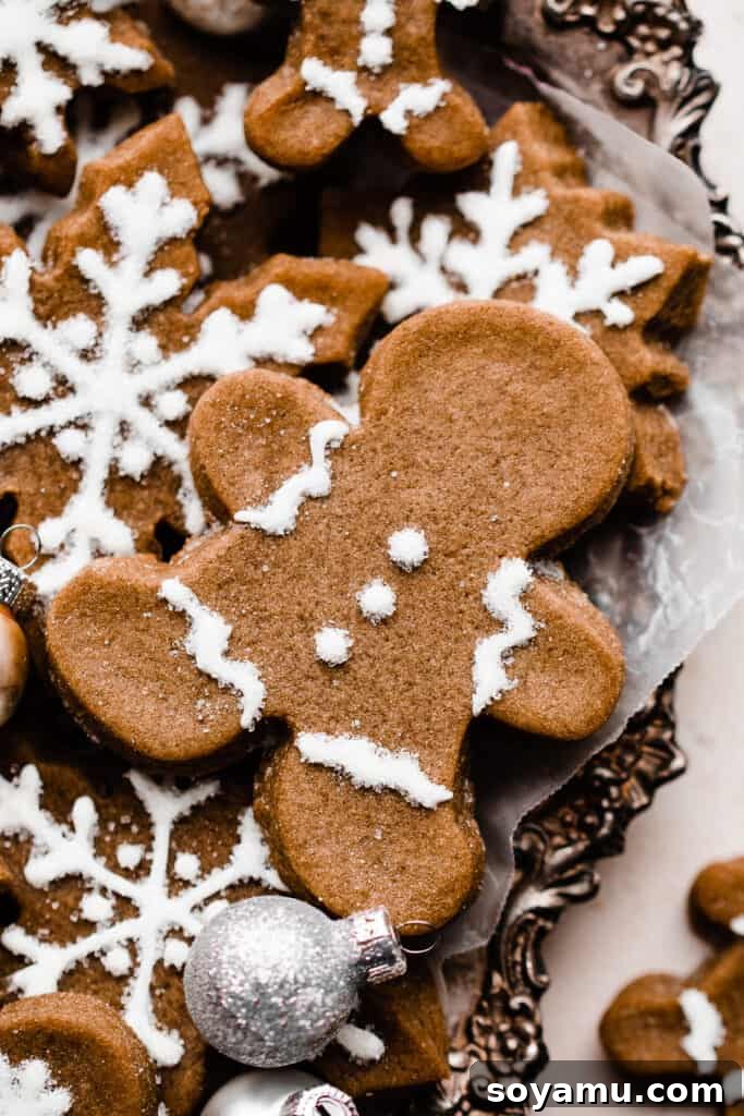 A charming close-up of a perfectly decorated gingerbread man cookie resting on a pile of other gingerbread cookies, highlighting the detail and softness.