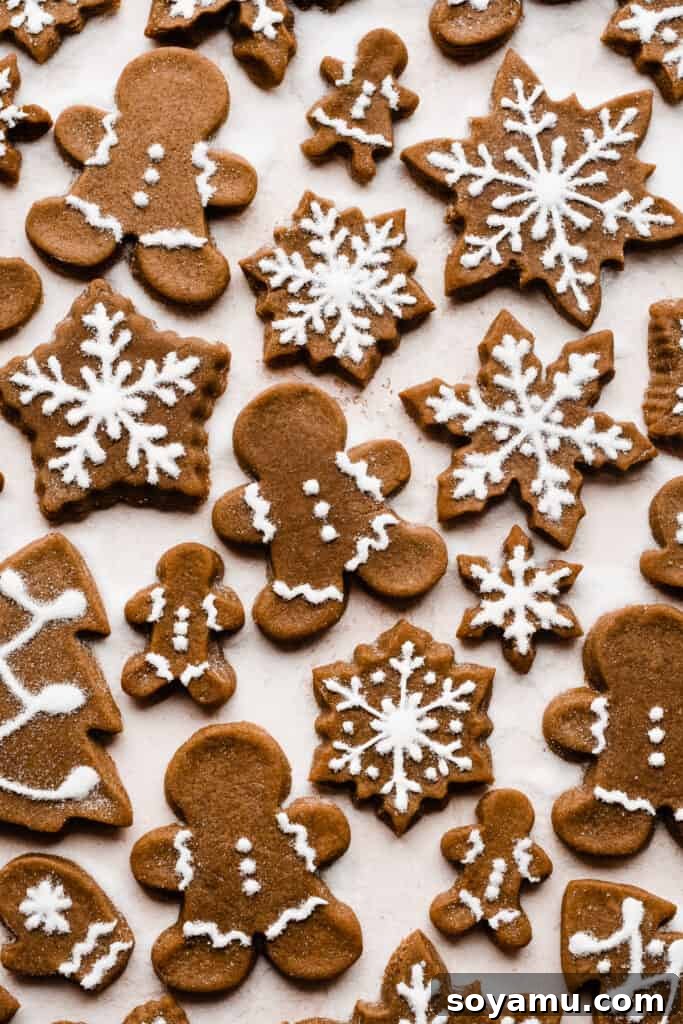 A beautiful arrangement of gingerbread cookies in various shapes like gingerbread men, stars, and snowflakes, all exquisitely decorated with white royal icing.