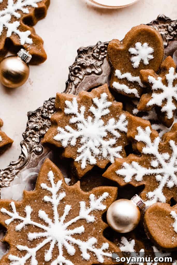 A close-up shot of a delicate snowflake-shaped gingerbread cookie, elegantly placed in a silver decorative tray, ready for serving.