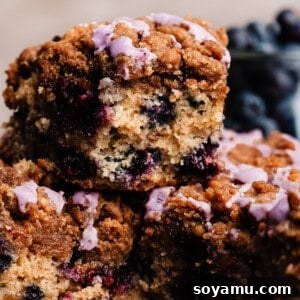 A piece of blueberry coffee cake stacked on other slices.
