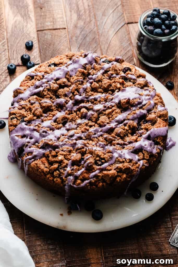 Blueberry Streusel Coffee Cake 8 The freshly baked and glazed blueberry coffee cake presented on a cake plate, glistening with sweet icing.