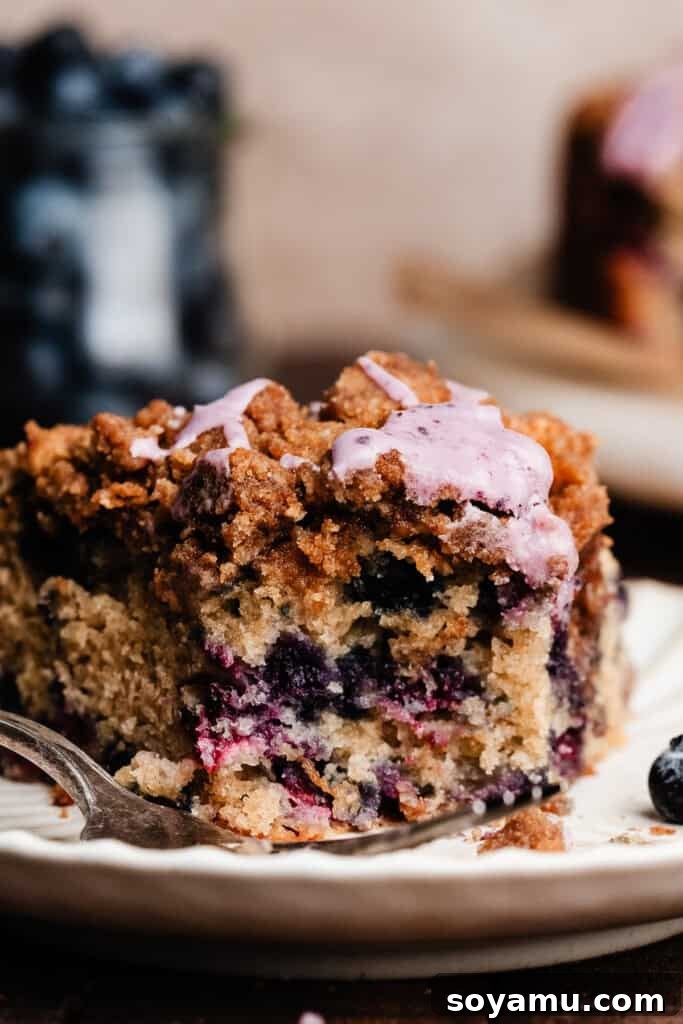 Blueberry Streusel Coffee Cake 10 A close-up of a slice of the blueberry coffee cake on a plate, with a bite taken out, revealing the moist interior and abundance of blueberries.