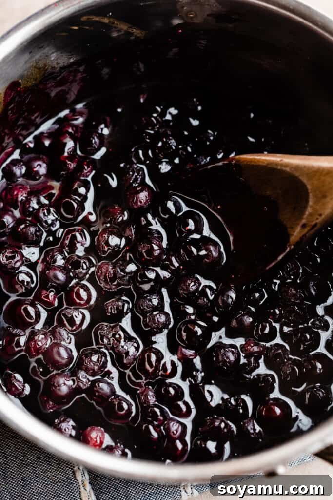 A pot of cooked blueberry sauce, thickened and ready, showing its rich, glossy texture.