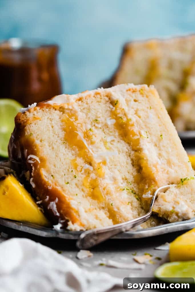 Piña Colada Dream Cake 3 A slice of the pineapple cake with visible layers of cake, frosting, and pineapple filling visible.