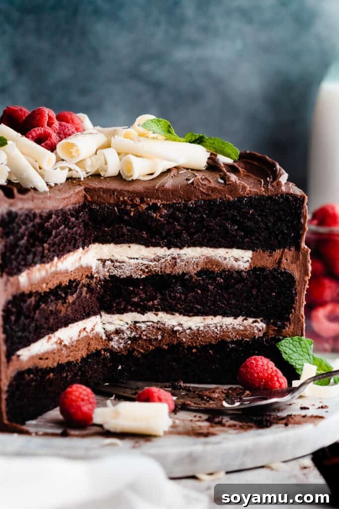 A cross-section of the sliced open cake with distinct layers of dark chocolate cake, creamy white chocolate ganache filling, and smooth chocolate fudge frosting.
