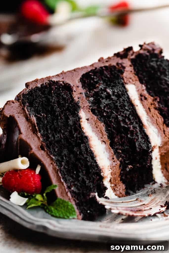 A close-up shot of a partially eaten slice of Tuxedo Cake, showcasing its irresistible layers of chocolate cake, white chocolate ganache, and chocolate frosting.
