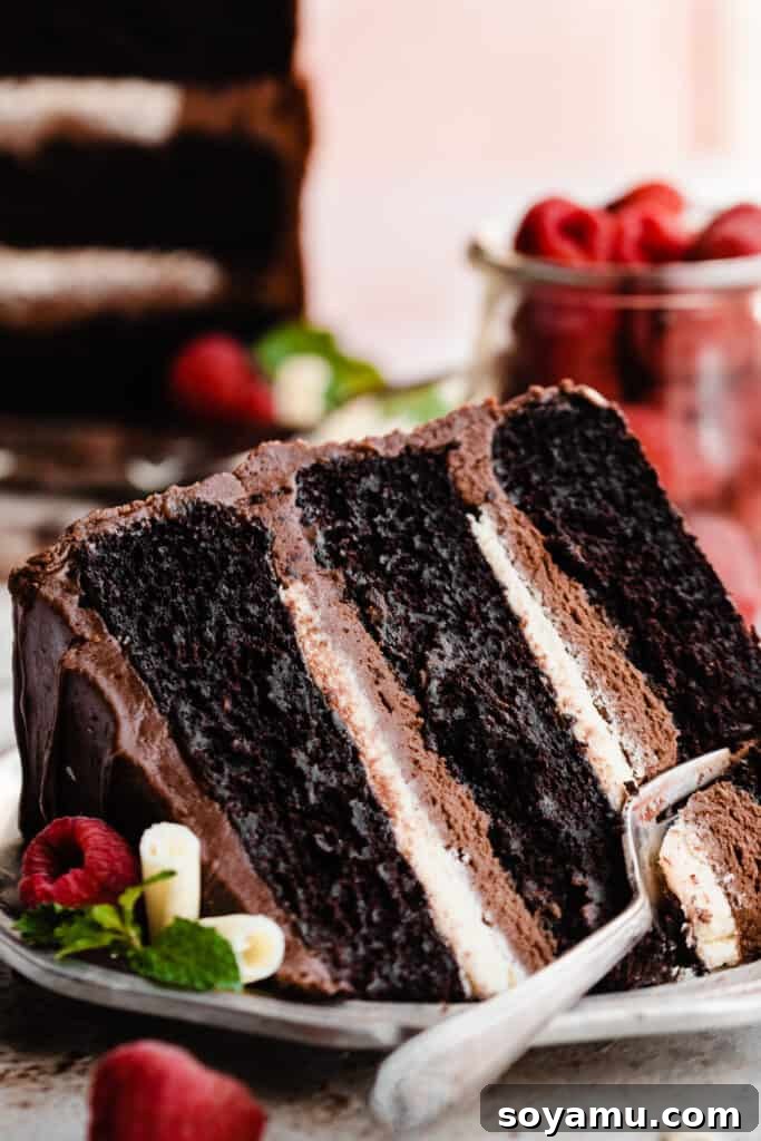 A close-up shot of a slice of Tuxedo Cake with a fork digging into its layers, highlighting the moist texture and creamy filling.