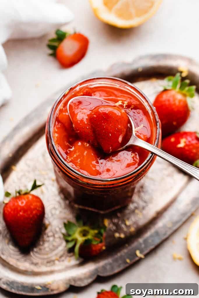 Fluffy Strawberry Pancakes with Speedy Strawberry Compote 4 A glass jar filled with vibrant red homemade strawberry compote, ready to top a stack of pancakes.