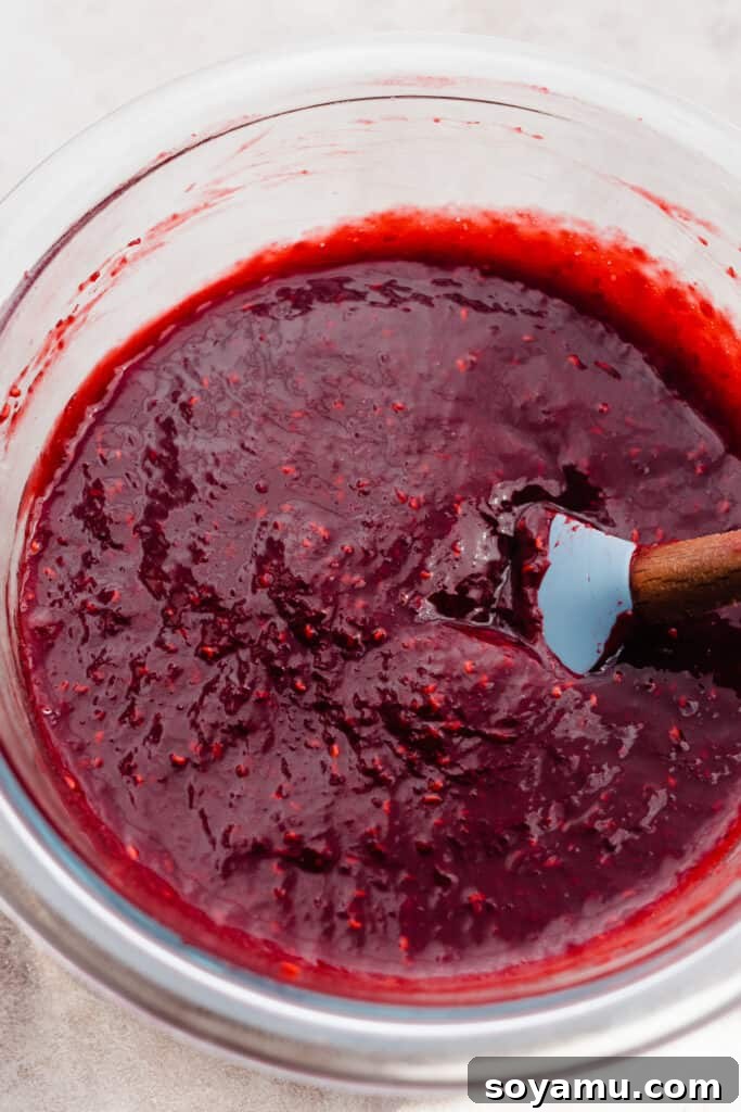 A bowl filled with freshly strained, smooth raspberry coulis, free of seeds.