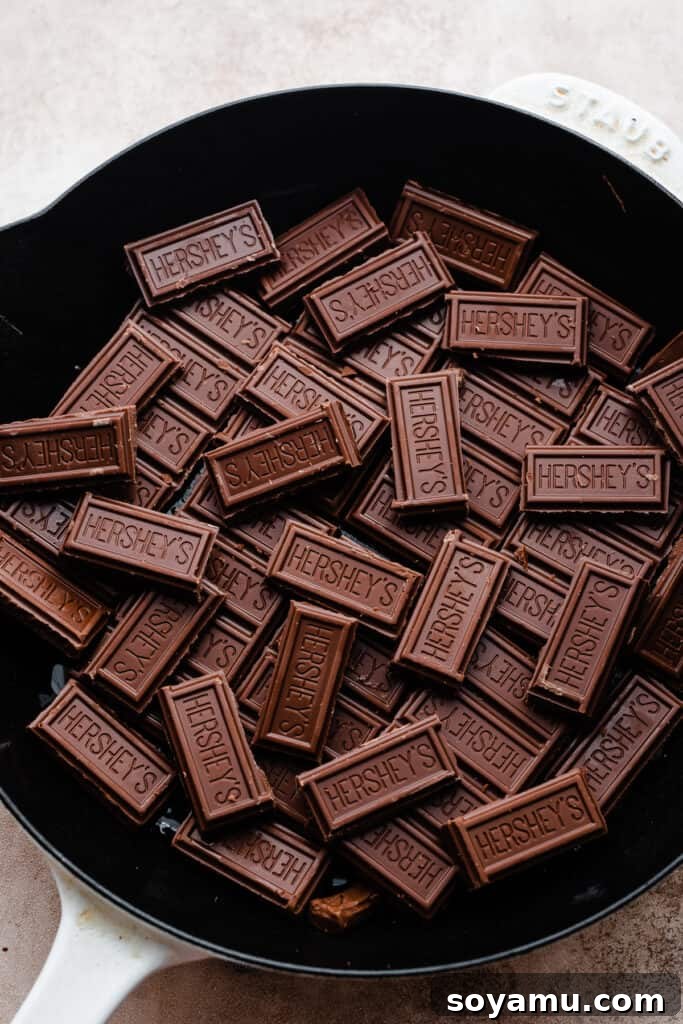 Simple 15 Minute Skillet Smores Dip 4 A cast iron skillet holds broken pieces of Hershey's milk chocolate bars, forming the initial delicious layer for the s'mores dip, ready for the next step.