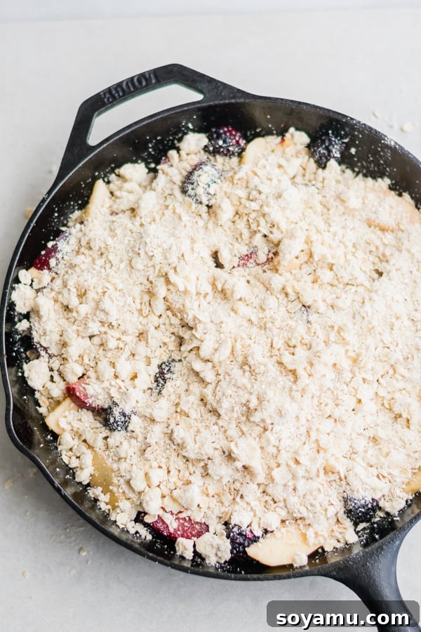 A serving of Summer Glory Skillet Crumble, glistening with fruit juices and golden topping, served in the skillet.