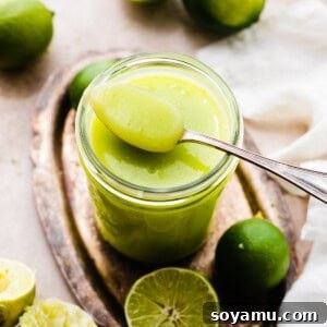 Zesty Homemade Lime Curd 12 A spoon resting on a jar of bright green lime curd.