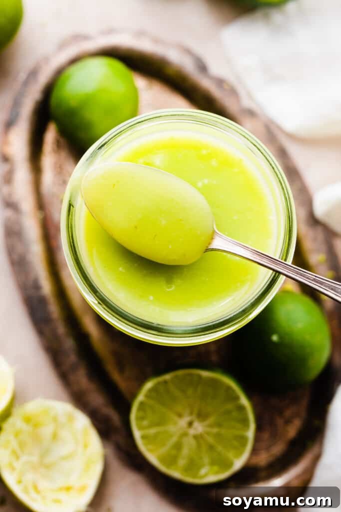 Zesty Homemade Lime Curd 10 A close-up of a spoon resting on a jar of lime curd.