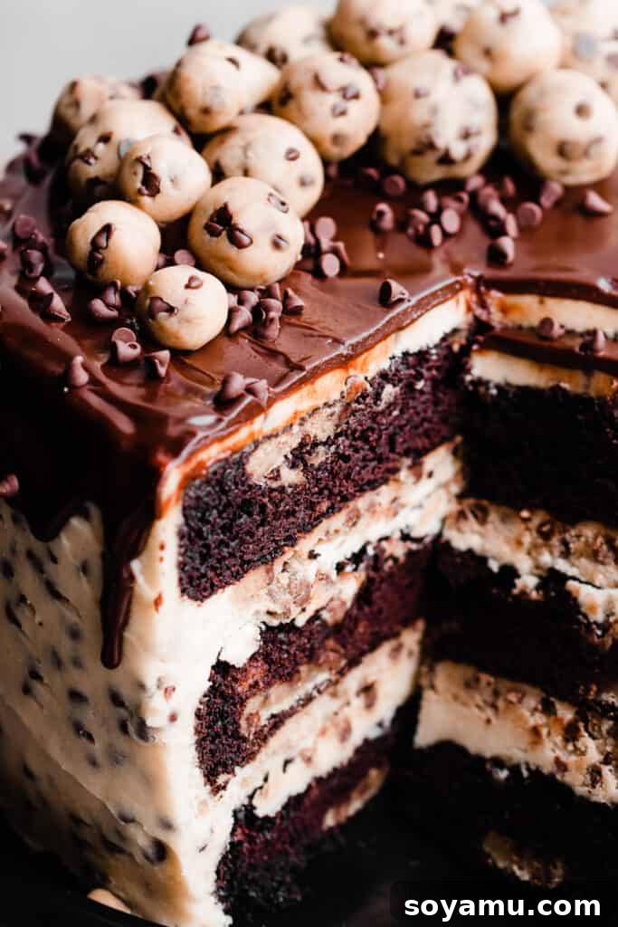 Decadent Cookie Dough Cake 11 A close-up of the inside of the cake, with visible layers of chocolate cake, edible cookie dough, cookie dough frosting, and chocolate drip.
